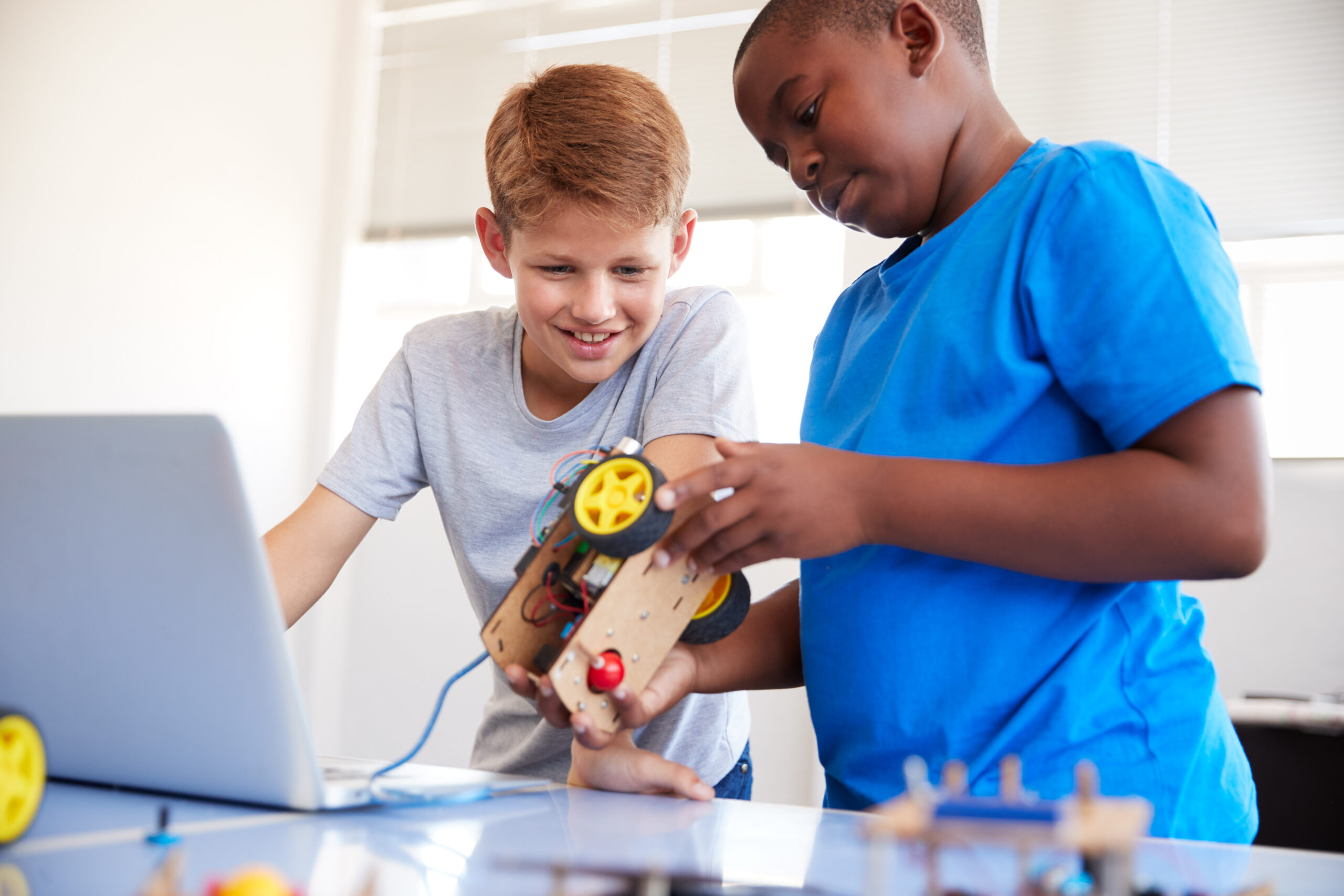 Two Male Students Building And Programing Robot Vehicle In After School Computer Coding Class