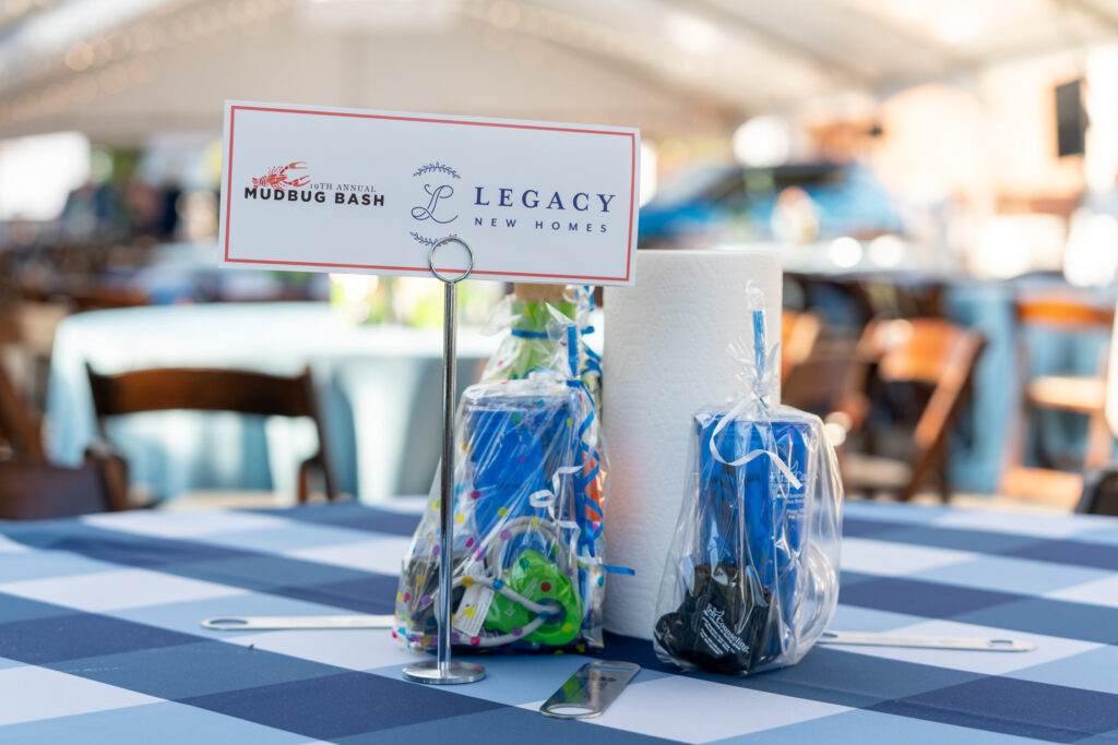 legacy new homes logo on an event sign at the 19th annual mudbug bash benefiting palmer home for children