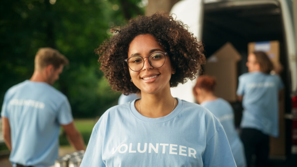 a woman wearing a volunteer t-shirt smiles at the camera