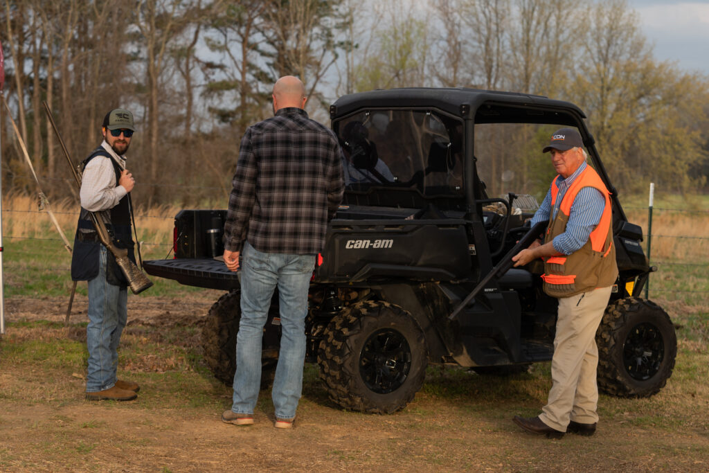 group of men with guns standing by an atv at a clay shoot